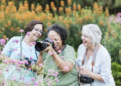 Three Senior Women with Cameras in Garden